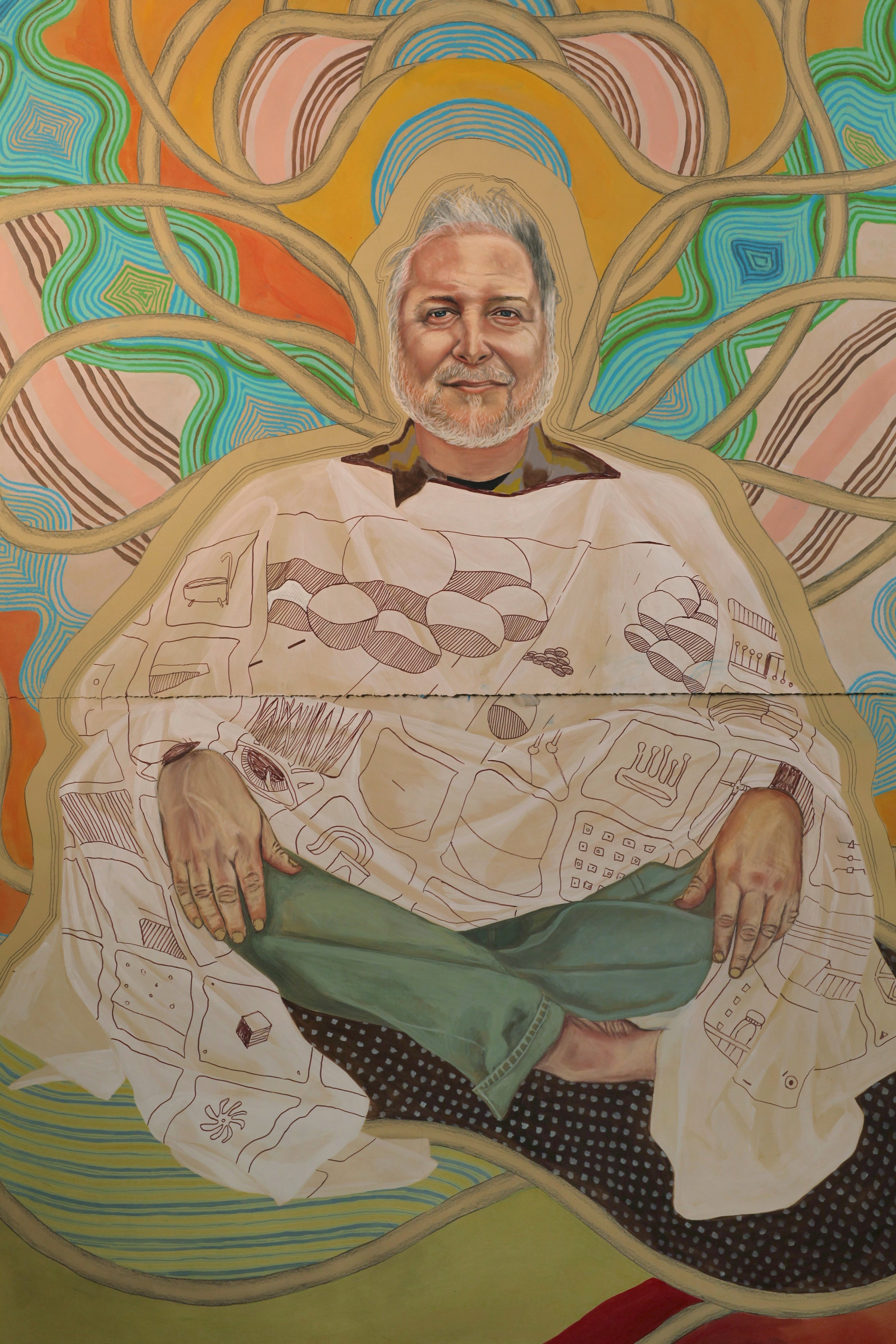A colorful painted portrait of a seated Stephen Bushman with white hair and a beard, wearing a white robe with illustrated patterns and green pants, set against an abstract swirling background in yellow, orange, teal, and pink.